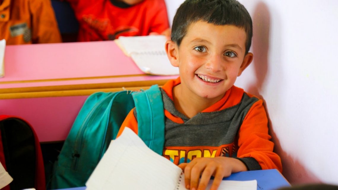 A young boy sitting at a table with a book in front of him