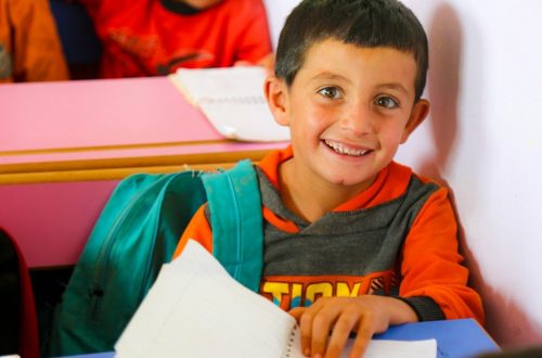 A young boy sitting at a table with a book in front of him