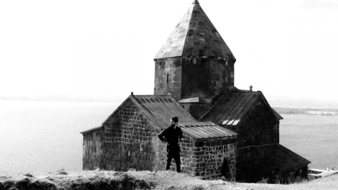 A black and white photo of a man standing in front of a church