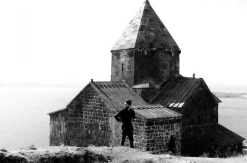 A black and white photo of a man standing in front of a church